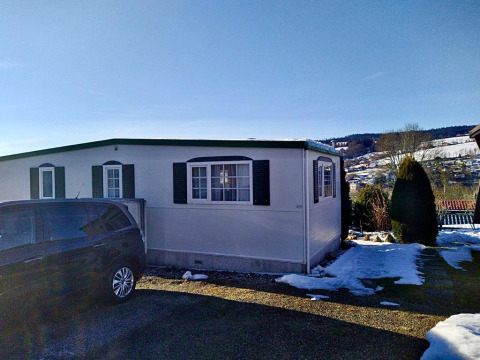 Lavandou mobile home at Camping Lac des Brenets, Switzerland, with a car parked and snow on the ground.