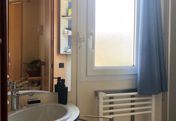 Badeværelse i Lavandou mobilhome ved Camping Lac des Brenets, Schweiz, med håndvask og vindue.