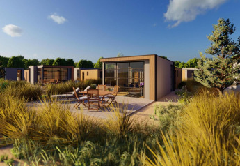 Vista esterna del lodge Cube Exclusif con design moderno, patio arredato e paesaggio naturale verde.
