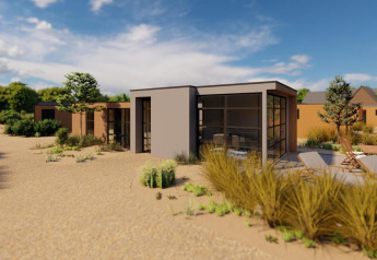 Cube Exclusif lodge en EuroParcs De Zeeuwse Duinen, Países Bajos, casa moderna rodeada de paisaje arenoso.