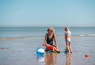 Een vrouw en een meisje spelen met strandballen en zand speelgoed bij EuroParcs De Zeeuwse Duinen, Nederland.