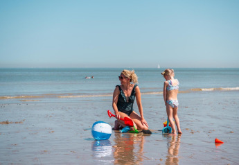 Eine Frau und ein Kind spielen mit Strandspielzeug am Wasser bei EuroParcs De Zeeuwse Duinen, Niederlande.