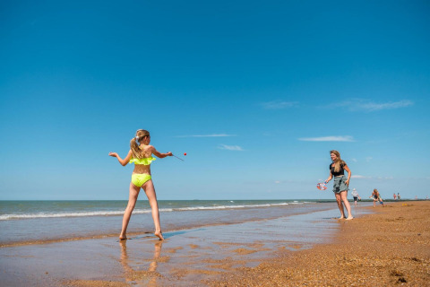 Due persone giocano insieme sulla spiaggia di Cube Exclusif a EuroParcs De Zeeuwse Duinen, Paesi Bassi, sotto un cielo blu.