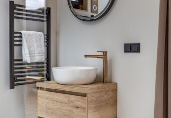 Moderne badeværelse i Tiny Wellness Suite på Holiday Park De IJsvogel, med vask, trækabinet og sort håndklædetørrer.