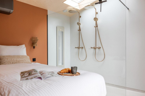 Moderne Tiny Wellness Suite bij Holiday Park De IJsvogel, Nederland, met dubbele douche en ontbijt op bed.