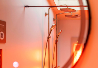 Doccia e soffioni a pioggia nella Tiny Wellness Suite presso Holiday Park De IJsvogel, Paesi Bassi, con luce calda.