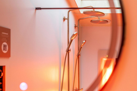 Ducha y rociadores tipo lluvia en la Tiny Wellness Suite del Holiday Park De IJsvogel, Países Bajos, con luz cálida.