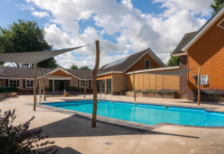 Outdoor swimming pool at the Tiny Wellness Suite in Holiday Park De IJsvogel, surrounded by modern cabins.