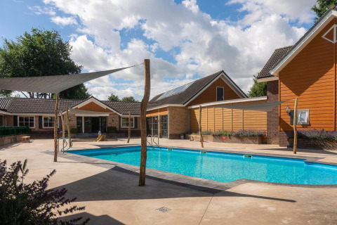 Buitenzwembad bij de Tiny Wellness Suite op Vakantiepark De IJsvogel, omgeven door moderne huisjes.