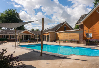 Buitenzwembad bij de Tiny Wellness Suite op Vakantiepark De IJsvogel, omgeven door moderne huisjes.