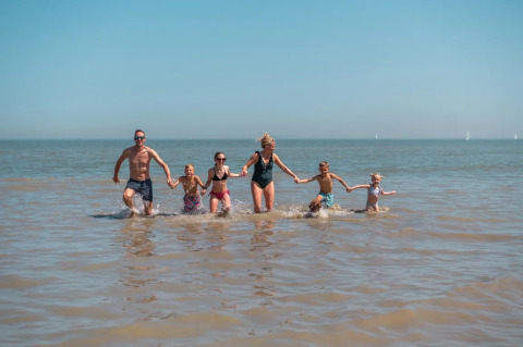 Familia disfruta en el mar en EuroParcs De Zeeuwse Duinen, parque vacacional en Zeeland, Países Bajos, día soleado.