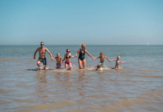 Familie leger sammen i havet ved EuroParcs De Zeeuwse Duinen feriepark i Zeeland, Holland på en solskinsdag.