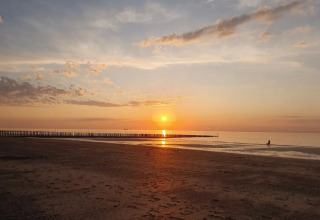 Solnedgang over stranden ved EuroParcs De Zeeuwse Duinen feriepark i Zeeland, Holland med roligt hav.