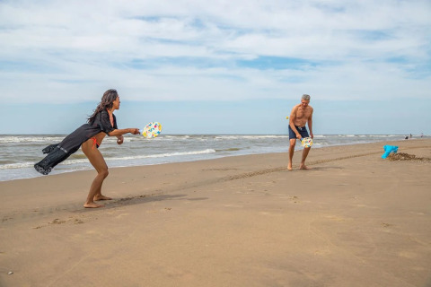 Two people play beach paddle tennis on the sand at EuroParcs De Zeeuwse Duinen in Zeeland, Netherlands.