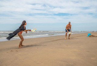 Zwei Menschen spielen Strandtennis am Meer im Ferienpark EuroParcs De Zeeuwse Duinen in Zeeland.