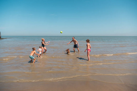 Gezin speelt met een bal in het ondiepe water bij EuroParcs De Zeeuwse Duinen in Zeeland, Nederland.