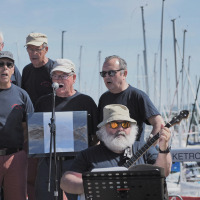 Hombres mayores interpretan música y cantan juntos cerca de un puerto en Trélévern, Bretaña, Francia.