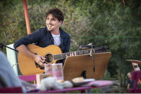 Man speelt gitaar en zingt buiten in Village Huttopia Lagoa de Óbidos vakantiepark, Centraal-Portugal.