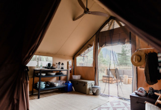 Interior view of a luxury tent at Village Huttopia Lagoa de Óbidos, featuring a terrace and camping gear.