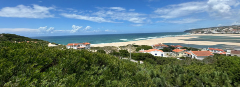 Vista panorámica de la playa, el océano y casas con tejados rojos en Huttopia Lagoa de Óbidos, Portugal central.