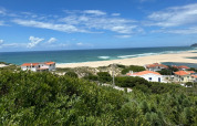 Panoramaudsigt over havet, sandstrand samt rødtagehuse ved Huttopia Lagoa de Óbidos i det centrale Portugal.