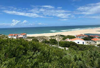 Panoramisch uitzicht op strand, zee en rode daken bij Huttopia Lagoa de Óbidos in Centraal-Portugal.