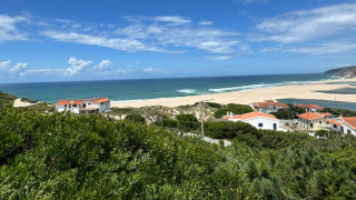 Vista panorámica de la playa, el océano y casas con tejados rojos en Huttopia Lagoa de Óbidos, Portugal central.