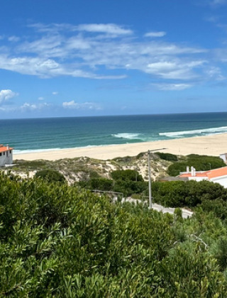 Vista panorámica de la playa, el océano y casas con tejados rojos en Huttopia Lagoa de Óbidos, Portugal central.