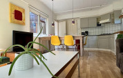 Bright retro kitchen and living area in Retro Lodge at Bungalowpark Het Verscholen Dorp, Netherlands, with yellow chairs.