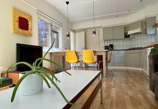 Stilfuldt retro køkken og stue i Retro Lodge på Bungalowpark Het Verscholen Dorp, Holland, med gule stole.