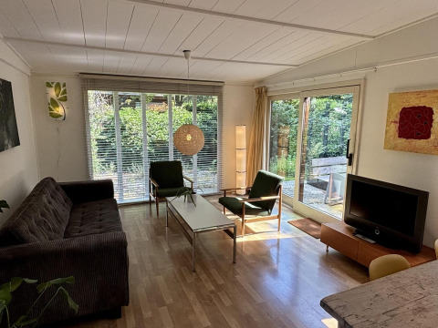 Stue i Retro Lodge ved Bungalowpark Het Verscholen Dorp med store vinduer og moderne indretning.