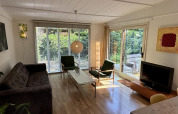 Stue i Retro Lodge ved Bungalowpark Het Verscholen Dorp med store vinduer og moderne indretning.