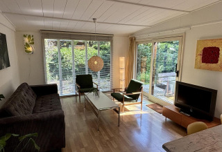 Stue i Retro Lodge ved Bungalowpark Het Verscholen Dorp med store vinduer og moderne indretning.