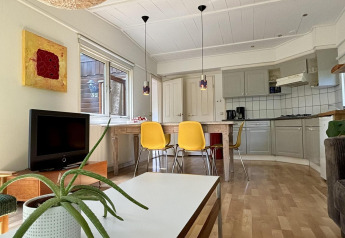 Acogedora cabaña con cocina moderna, sillas amarillas y planta en Retro Lodge, Het Verscholen Dorp, Países Bajos.