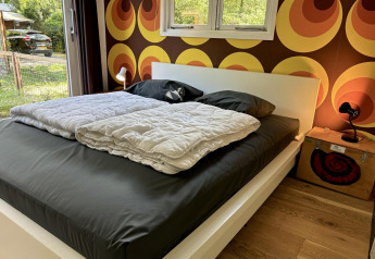 Dormitorio en Retro Lodge, Bungalowpark Het Verscholen Dorp, Países Bajos, con papel retro y cama moderna.