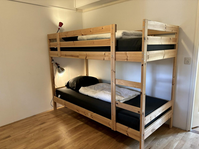 Kamer met houten stapelbed en twee leeslampjes in Retro Lodge, Bungalowpark Het Verscholen Dorp, Nederland.