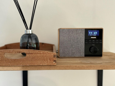 Moderne Philips-Radio und Duftspender auf einem Holzregal in der Retro Lodge von Bungalowpark Het Verscholen Dorp.