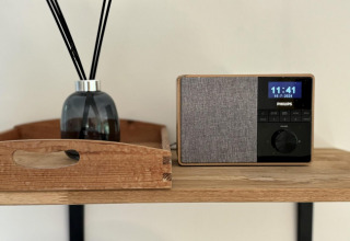Et stilfuldt bord i Retro Lodge med en moderne Philips radio og en duftspreder på Bungalowpark Het Verscholen Dorp.