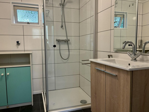 Modernes Bad im Retro Lodge, Bungalowpark Het Verscholen Dorp, Niederlande, mit Dusche und Waschbecken.
