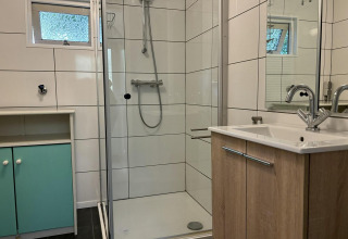 Moderne badeværelse i Retro Lodge, Bungalowpark Het Verscholen Dorp, Holland, med brusekabine og vask.