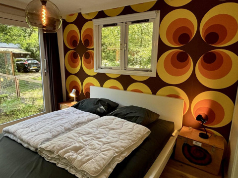 Schlafzimmer in der Retro Lodge im Bungalowpark Het Verscholen Dorp mit Retro-Tapete und Doppelbett.