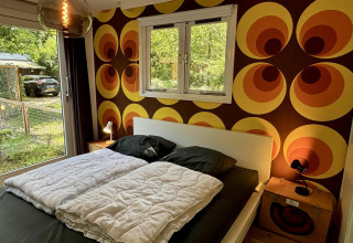 Dormitorio en Retro Lodge de Bungalowpark Het Verscholen Dorp con papel pintado retro y cama doble.