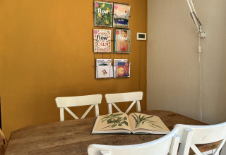 Acogedor rincón en Tiny Lodge Basic, Bungalowpark Het Verscholen Dorp, con sillas y revistas en la pared.