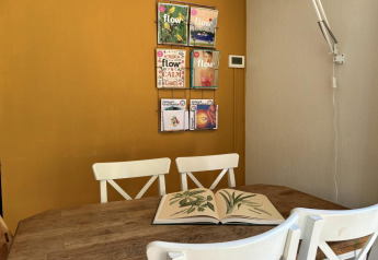 Accogliente angolo pranzo al Tiny Lodge Basic, Bungalowpark Het Verscholen Dorp, con riviste e libro aperto.