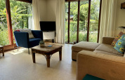 Salón moderno en Tiny Lodge Basic de Bungalowpark Het Verscholen Dorp con grandes ventanas y vistas al jardín.