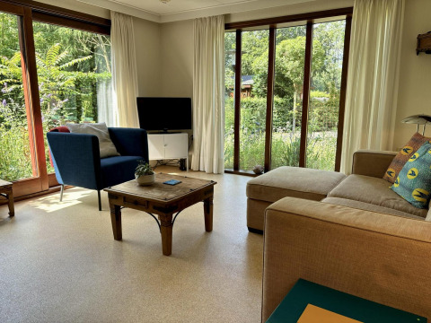 Salón moderno en Tiny Lodge Basic de Bungalowpark Het Verscholen Dorp con grandes ventanas y vistas al jardín.