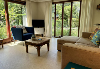 Salón moderno en Tiny Lodge Basic de Bungalowpark Het Verscholen Dorp con grandes ventanas y vistas al jardín.