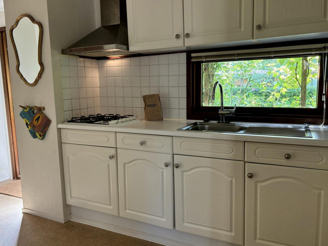 Cocina en Tiny Lodge Basic del Bungalowpark Het Verscholen Dorp, Países Bajos, con ventana a la naturaleza.