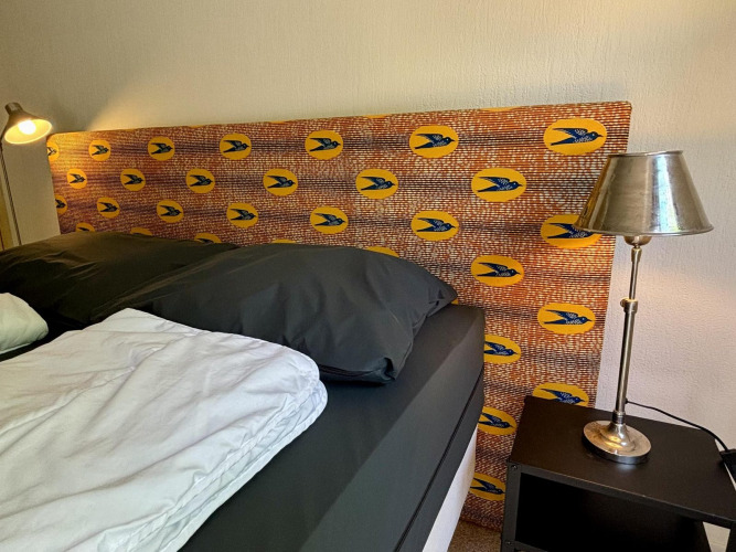 Dormitorio en Tiny Lodge Basic en Bungalowpark Het Verscholen Dorp, Países Bajos, con cabecero y lámparas modernas.