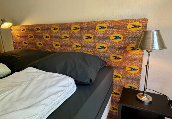 Camera da letto al Tiny Lodge Basic nel Bungalowpark Het Verscholen Dorp, Paesi Bassi, con testiera colorata e lampade.